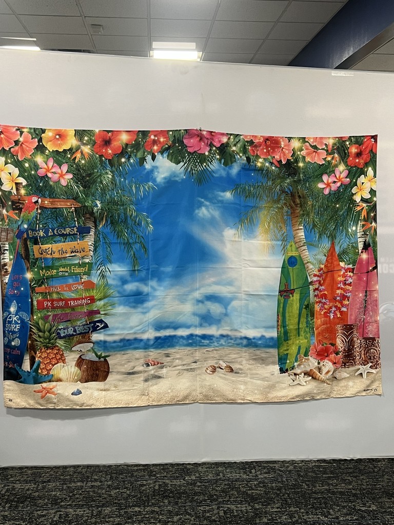 Tropical beach-themed backdrop featuring surfboards, palm trees, hibiscus flowers, and a wooden signpost with beach activities.