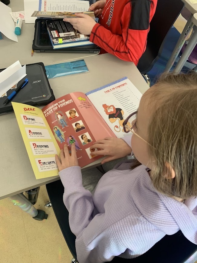 Close-up of a student reading a D.A.R.E. workbook featuring the D.A.R.E. mascot and a decision-making model.