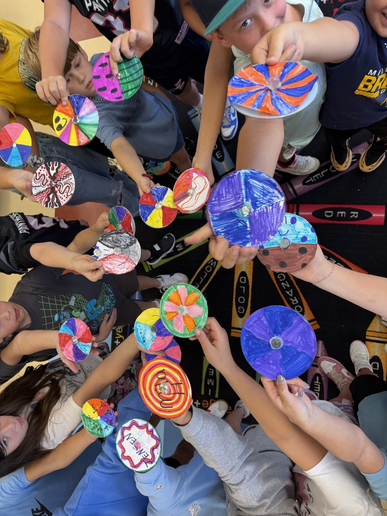 A group of students reaching toward the camera to display their colorful, color theory spinners