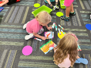Two young students sitting on the floor solving colorful picture strip puzzles during a classroom learning activity.