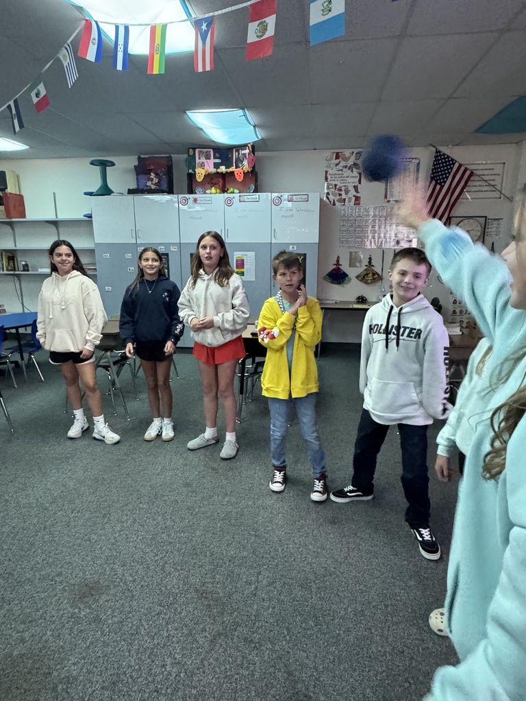 Line of students standing at the front of a classroom facing classmates during an interactive game
