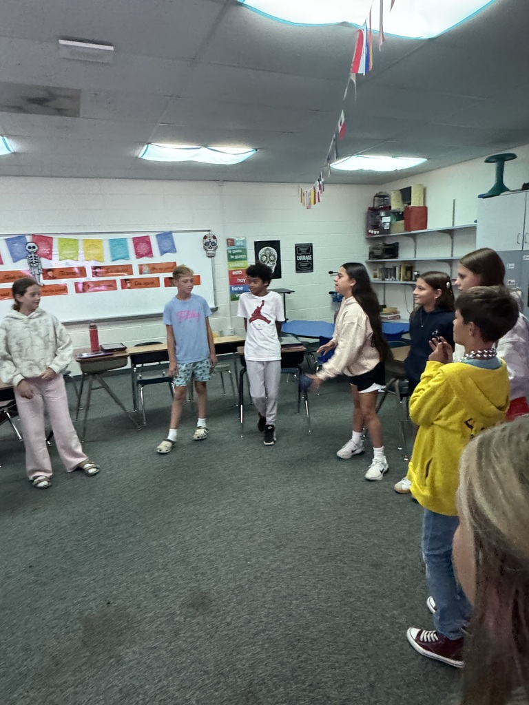 A student tossing a soft blue ball across the classroom to a classmate during an interactive group game.