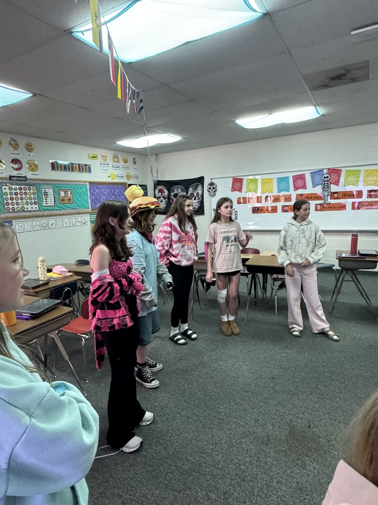 Middle school students standing around the perimeter of a classroom during an interactive group exercise.