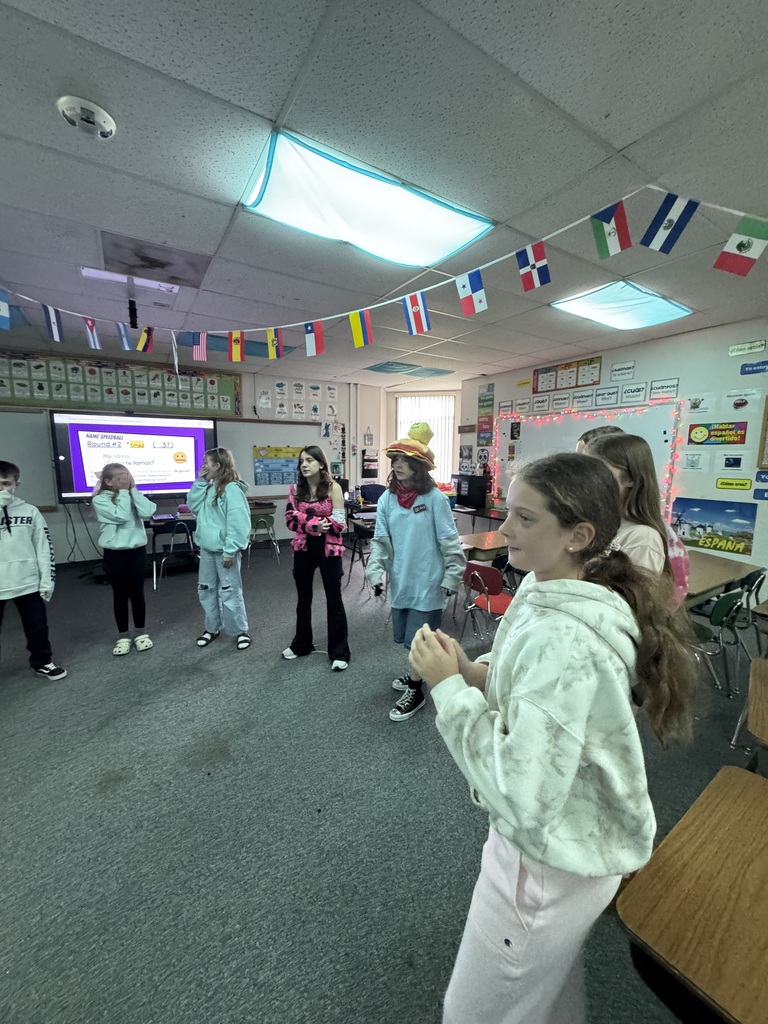 Middle school students standing in a large circle inside a classroom while participating in an interactive group activity.