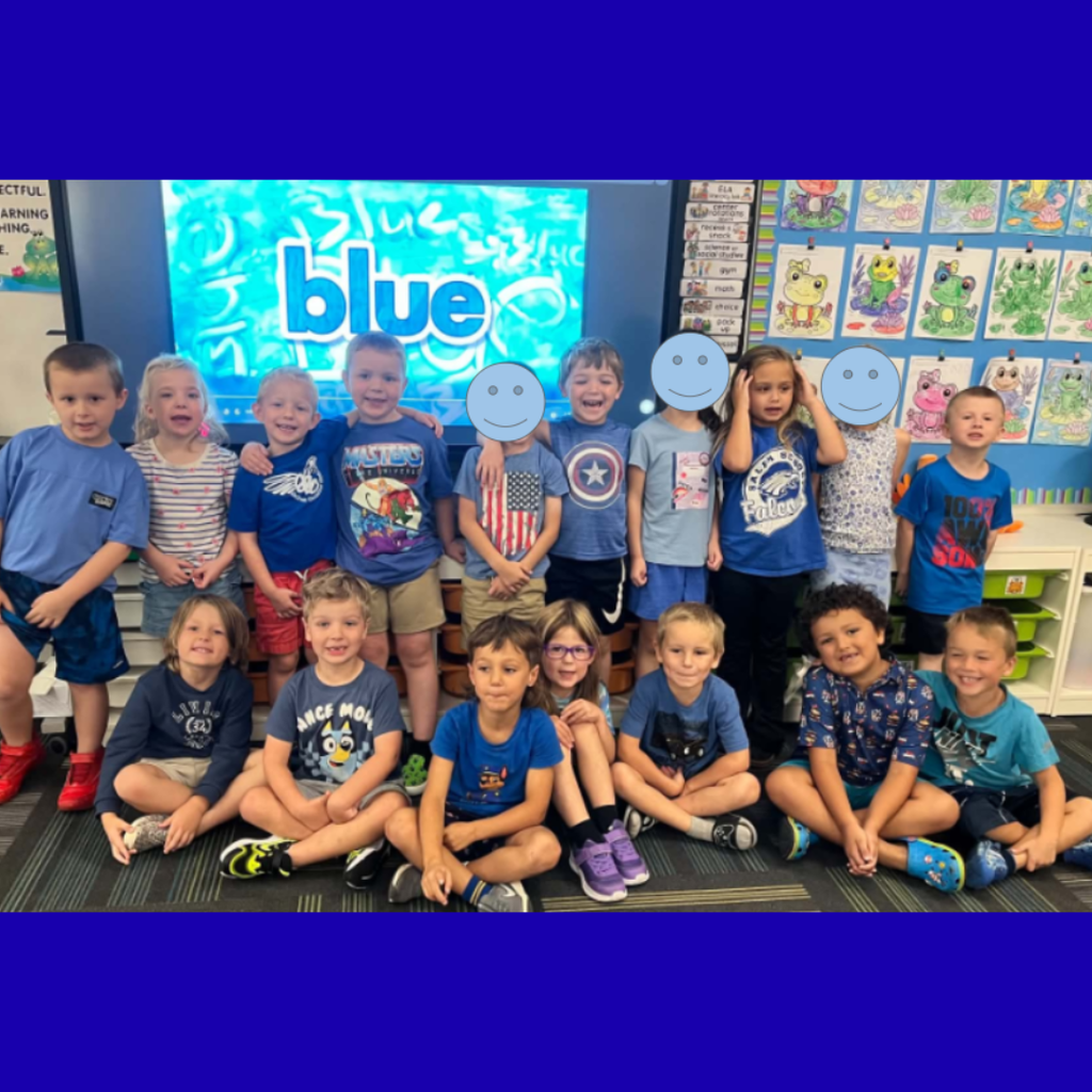 Elementary class posing together in blue clothing in front of a screen displaying the word "blue."