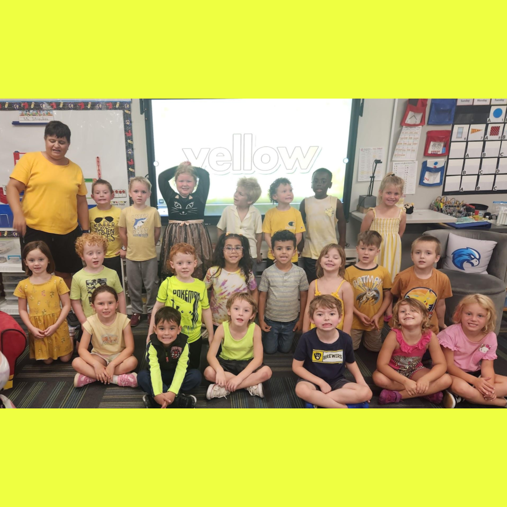 Group of elementary school students wearing yellow shirts gathered in a classroom for color day.
