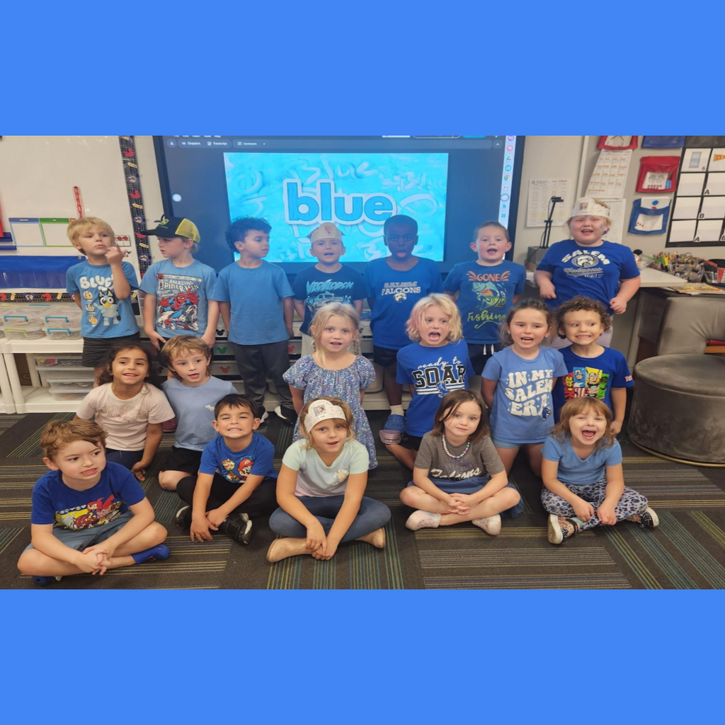 Elementary class posing together in blue clothing in front of a screen displaying the word "blue."