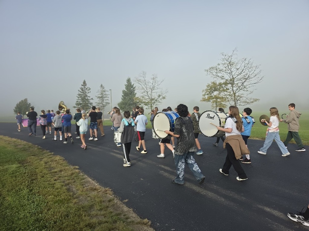 Middle school marching band outside practicing marching on the pavement on a foggy morning