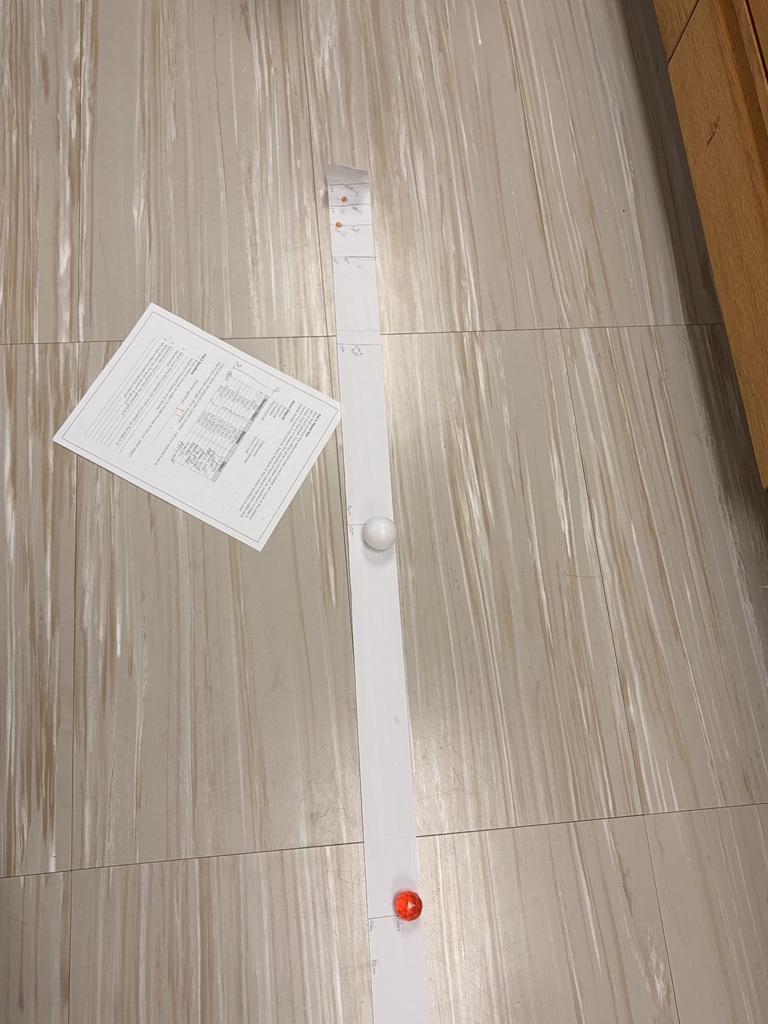 Top-down view of a paper scale on the floor next to worksheet papers and small plastic marker objects.