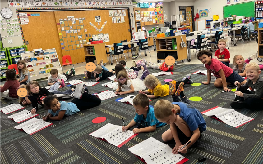 kindergarten students sitting on the carpte working in number folder on creation of numbers