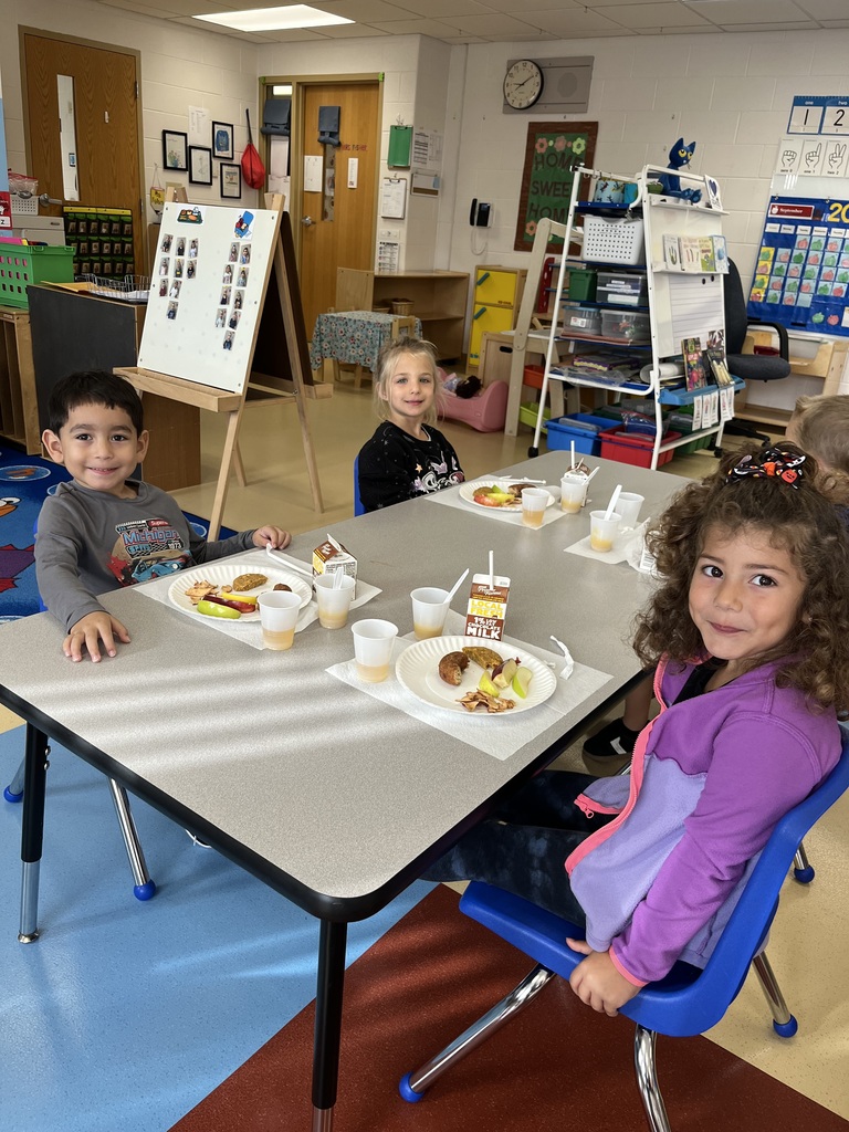 Three 4K students sitting at a classroom table during an apple tasting activity