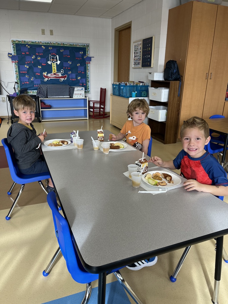 Three 4K students sitting at a classroom table during an apple tasting activity