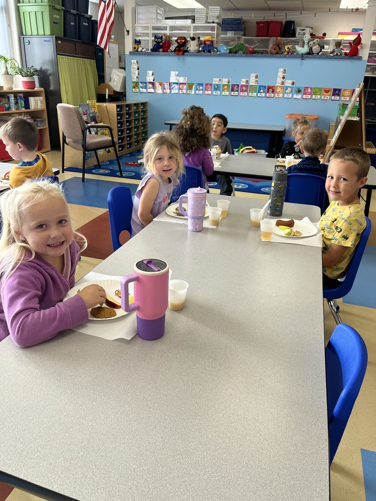 Three 4K students sitting at a classroom table during an apple tasting activity