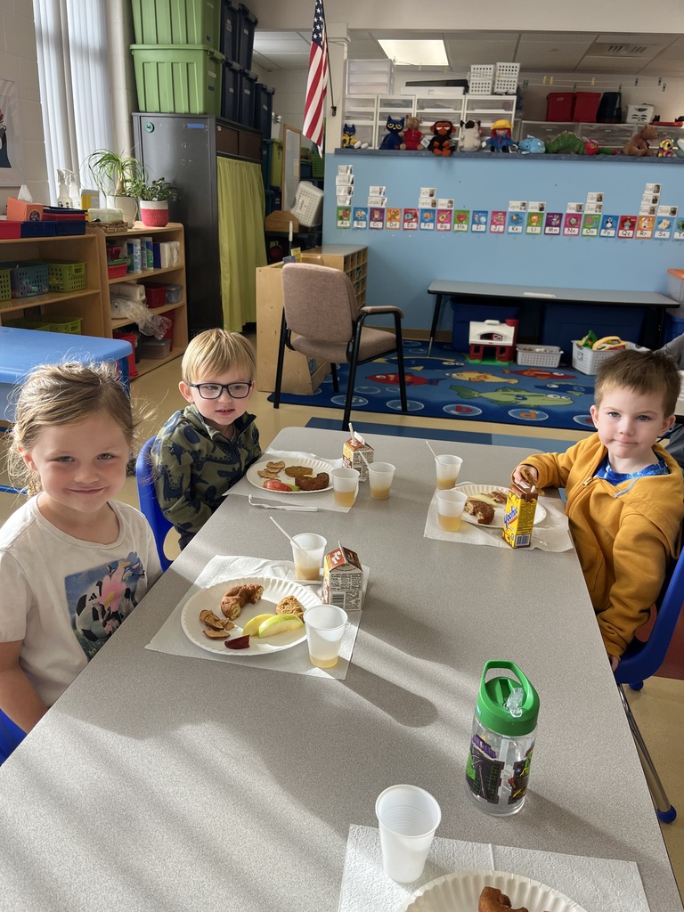 Three 4K students sitting at a classroom table during an apple tasting activity
