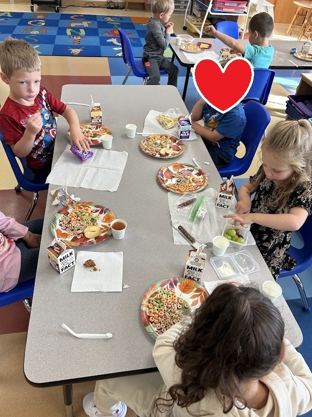 Elementary students sitting around a classroom table during a snack time activity.