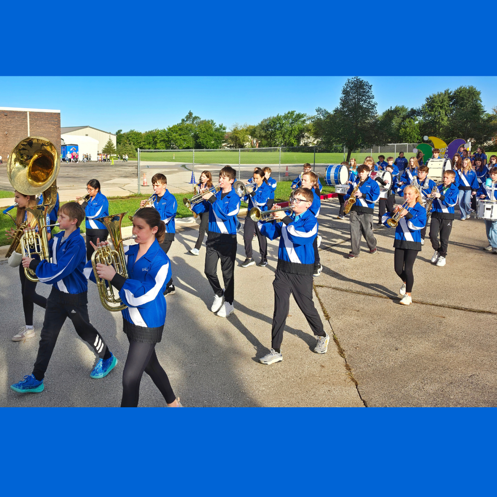 School marching band members playing brass and woodwind instruments while marching outdoors in a line on a sunny day.