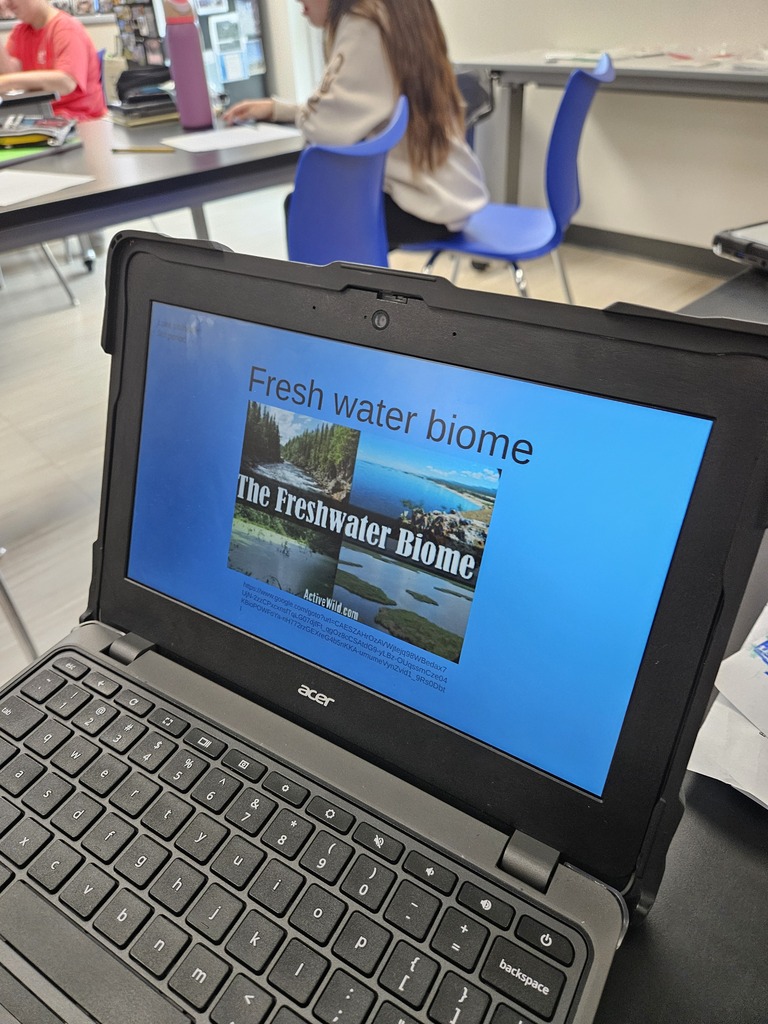 Close-up of a student's laptop screen displaying a presentation slide titled "Fresh water biome" during a classroom lesson.