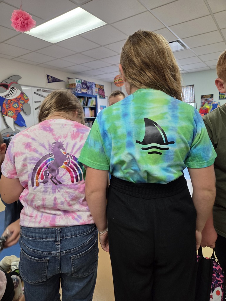Back view of two students wearing tie-dye shirts featuring unicorn and shark fin designs.