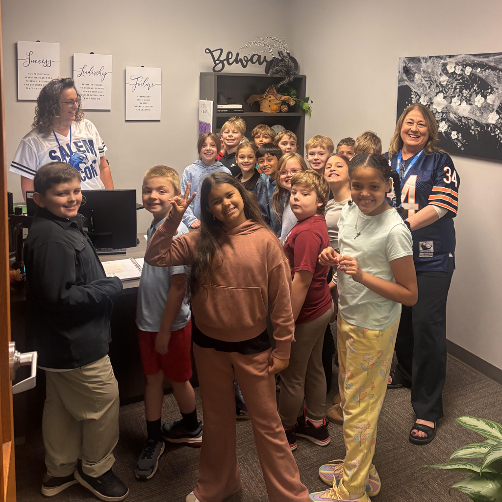 office full of students and 2 adults smiling after leading the pledge