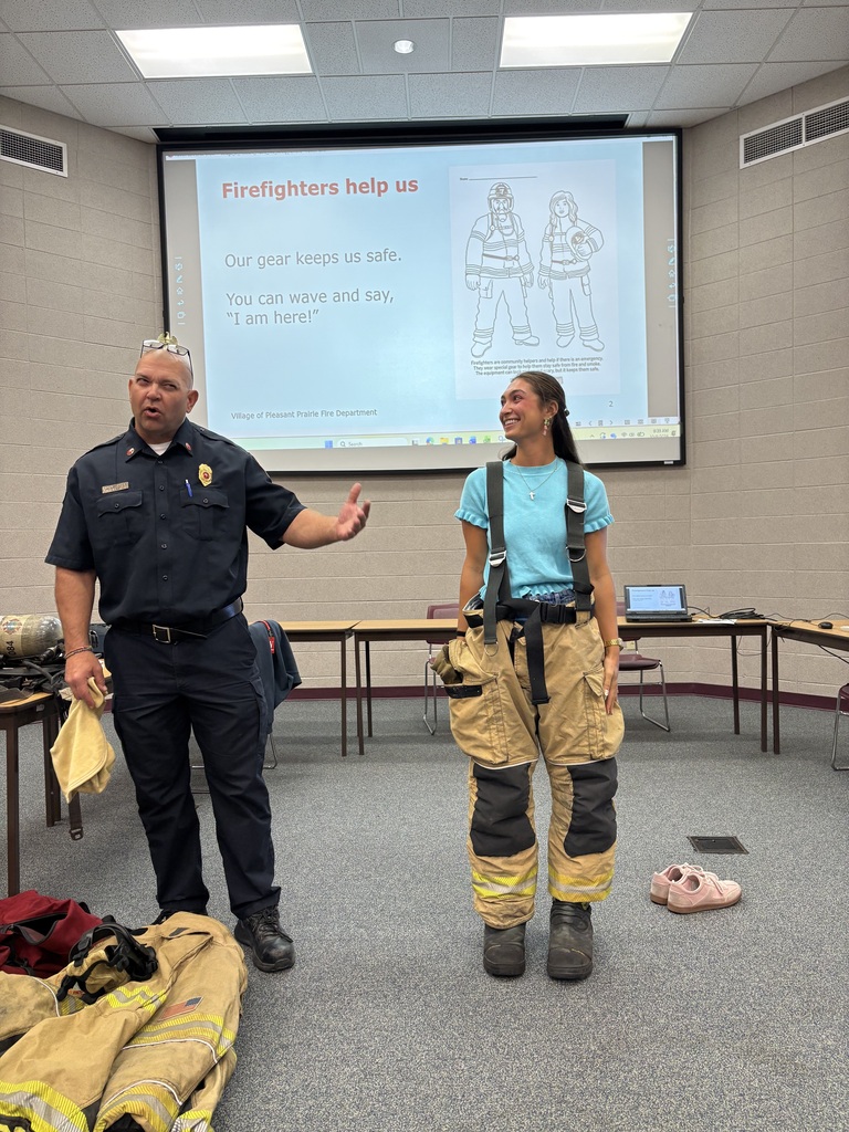 Ms. Longrie with Firefighter Aaron talking about fire safety in a presentation