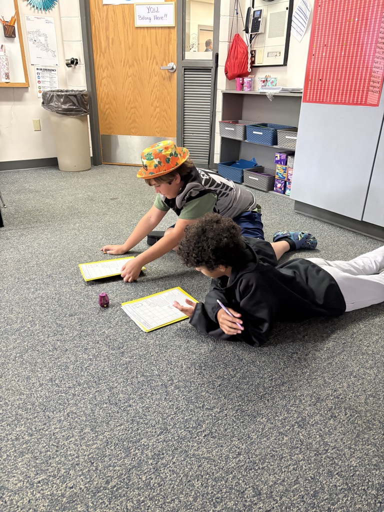 2 middle school students sitting on the carpet in the classroom working together on their classwork.