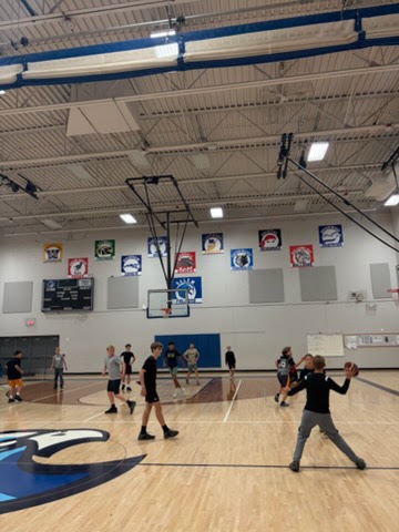 A student getting ready to pass a football to classmates during a gym game on the school court.