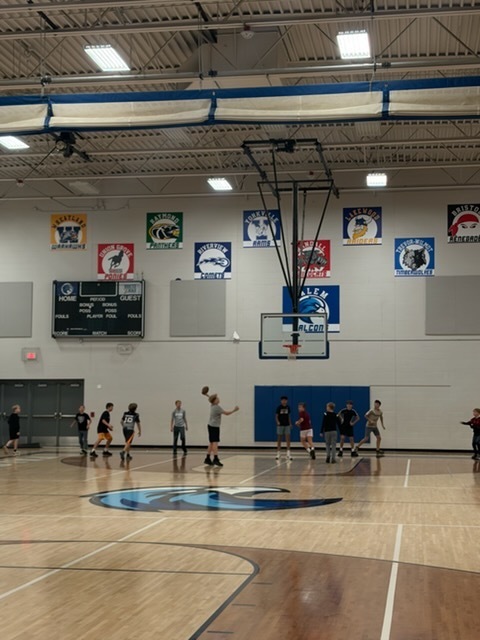 A student preparing to throw a football during an indoor open gym activity on the basketball court.
