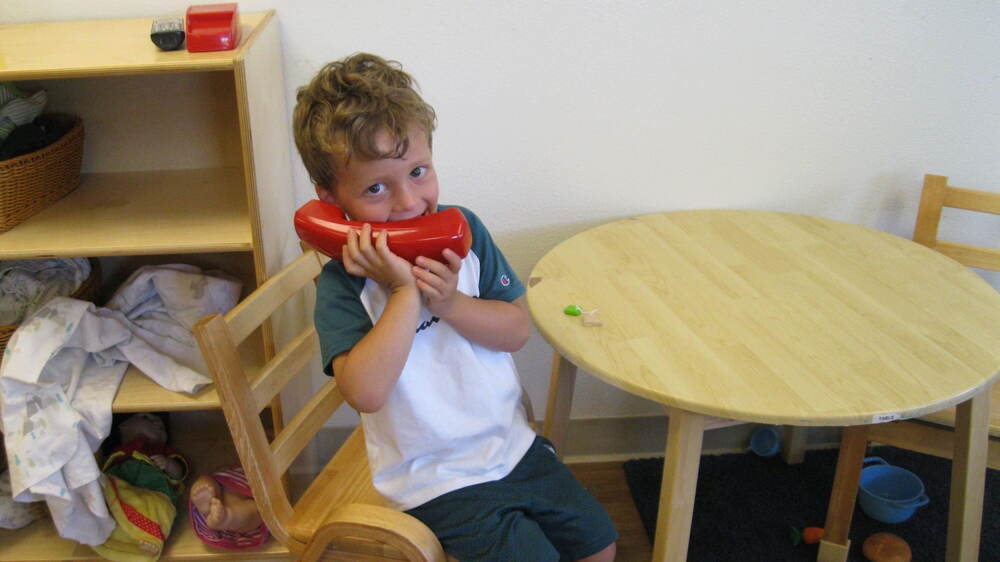 An ECC student pretends to talk on a phone in their classroom. 