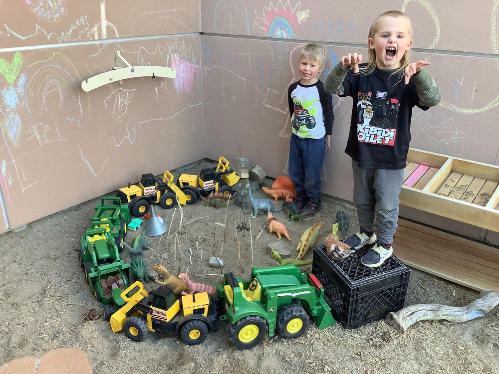 Two SECC students pose as dinosaurs in the sand box while showing off their Jurassic World set up