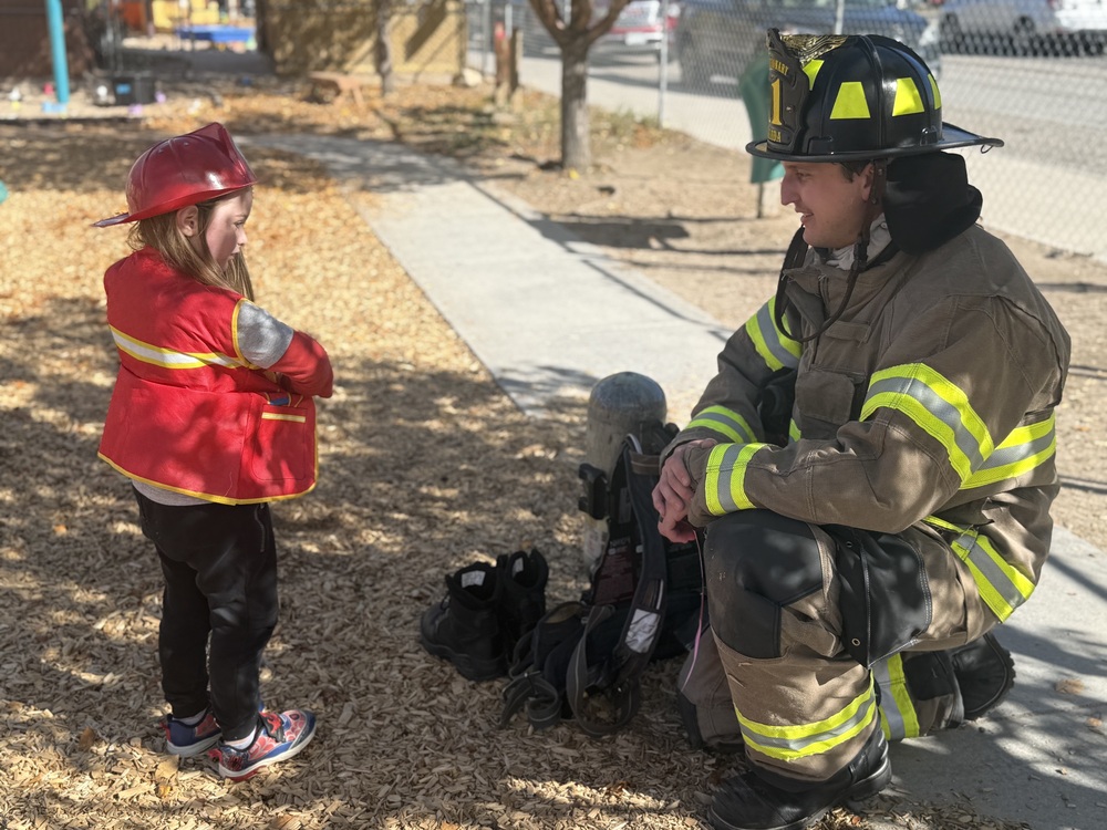 An ECC student shows her fire fighter jacket to the fireman.