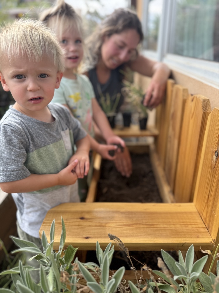Two SECC students help plant vegetables in a new planter on the playground.