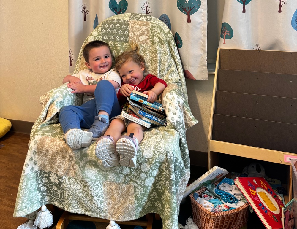 Two students snuggle on a rocking chair with books