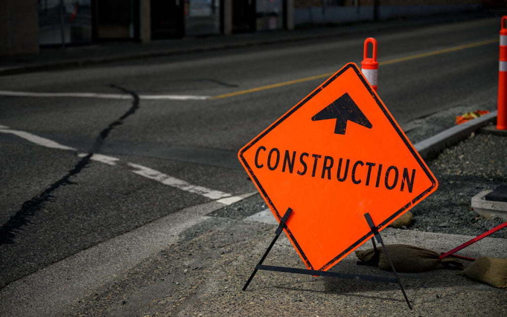 Orange construction sign on pavement - stock photo