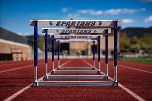 Hurdles with the Spartan logo set on the SHS track  with mountains and blue sky in the background