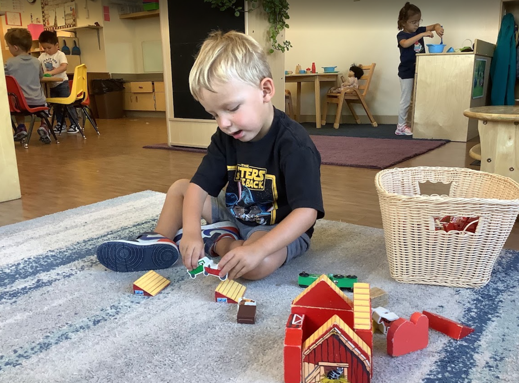 A ECC student plays with toys on the rug in his classroom. 