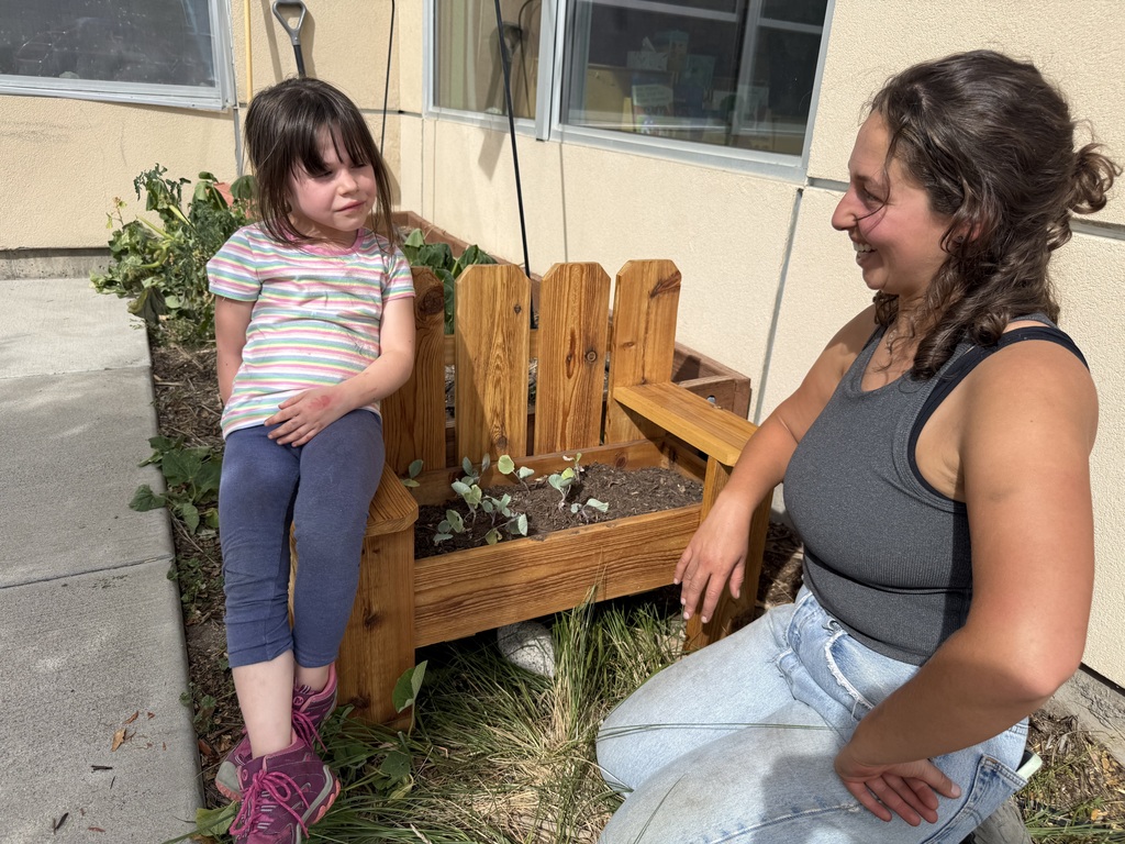 A SECC student relaxes on the side of the new planter on the playground. 