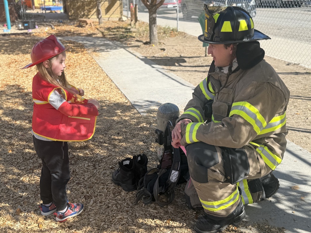 An ECC student wearing a fire person costume stands with a fireman in gear.