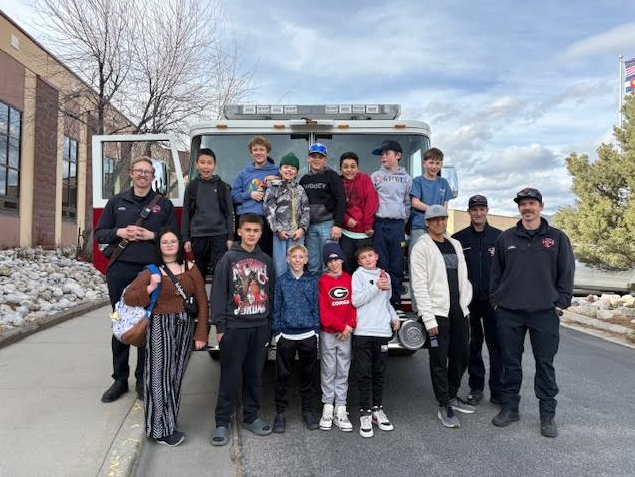 Students posing in front of the firetruck and a student trying on bunker gear!