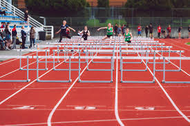 athletes jumping hurdles in a meet