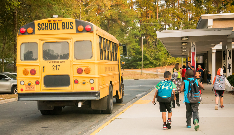 students walking off school bus into school