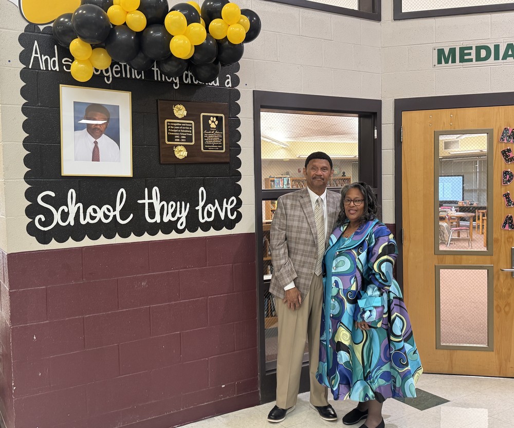 Gerald Johnson and wife standing beside dedication outside Media Center