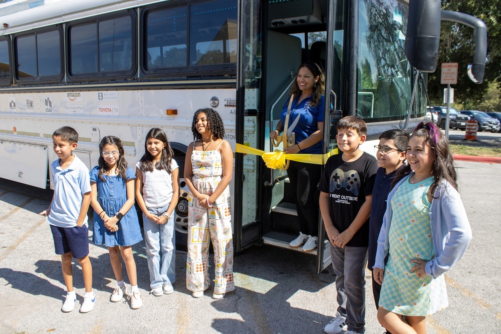 Principal and students prepare to cut yellow ribbon on bus
