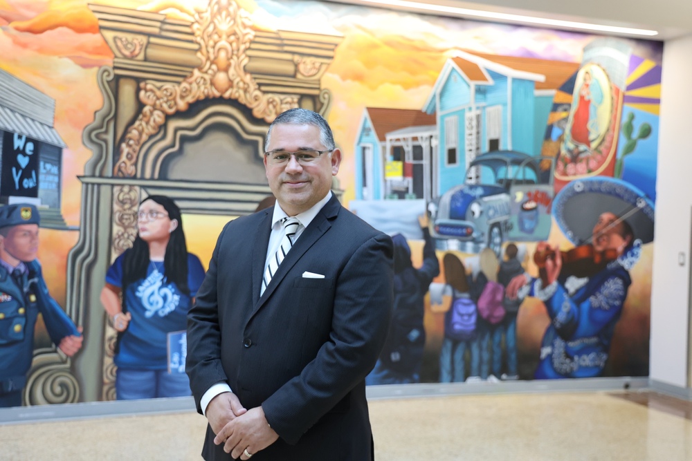 Principal Flores stands in front of Lanier Mural