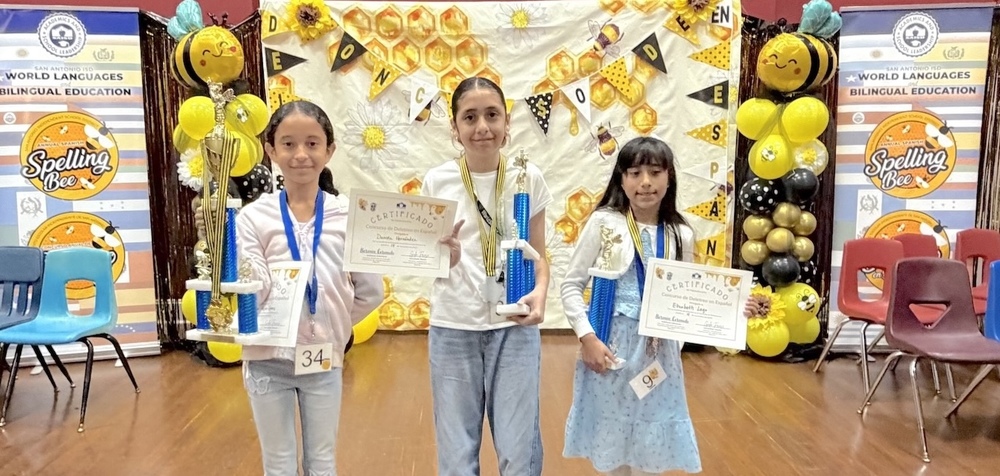Three girls hold trophies and certificates
