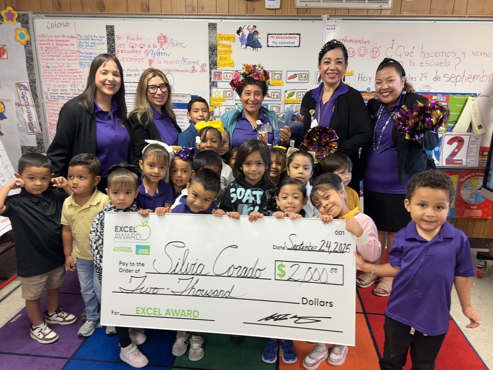 Teacher stands with class, principals and big check for $2,000