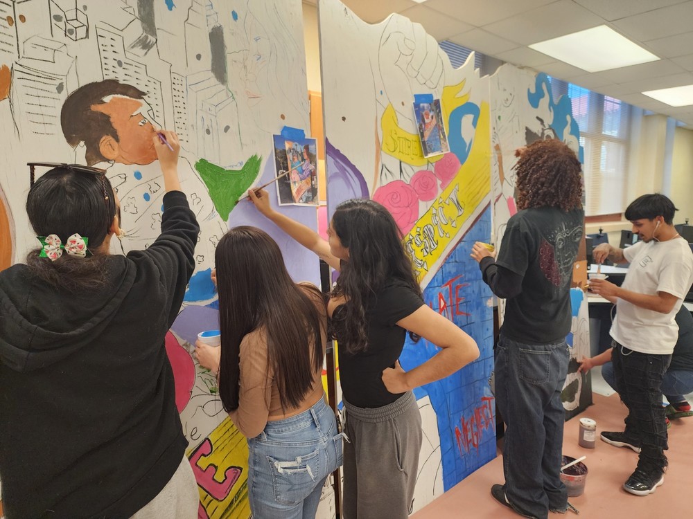 Students work paint a wall mural