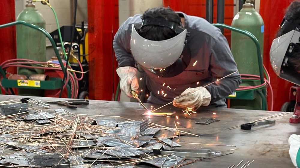 Student welding with sparks