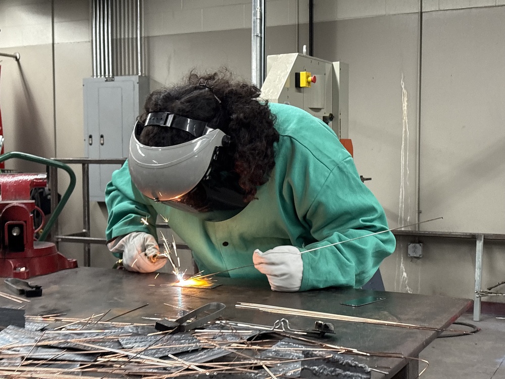 Male student welds a long piece of wire
