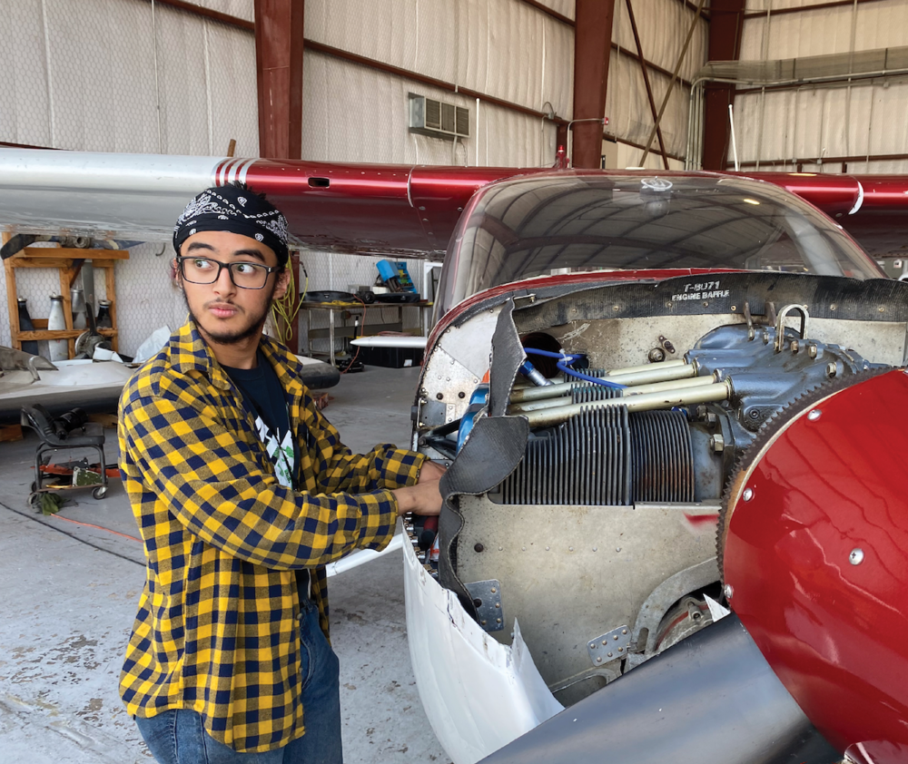 Male student stands by small airplane