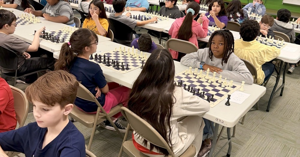 students playing chess at tables lined up